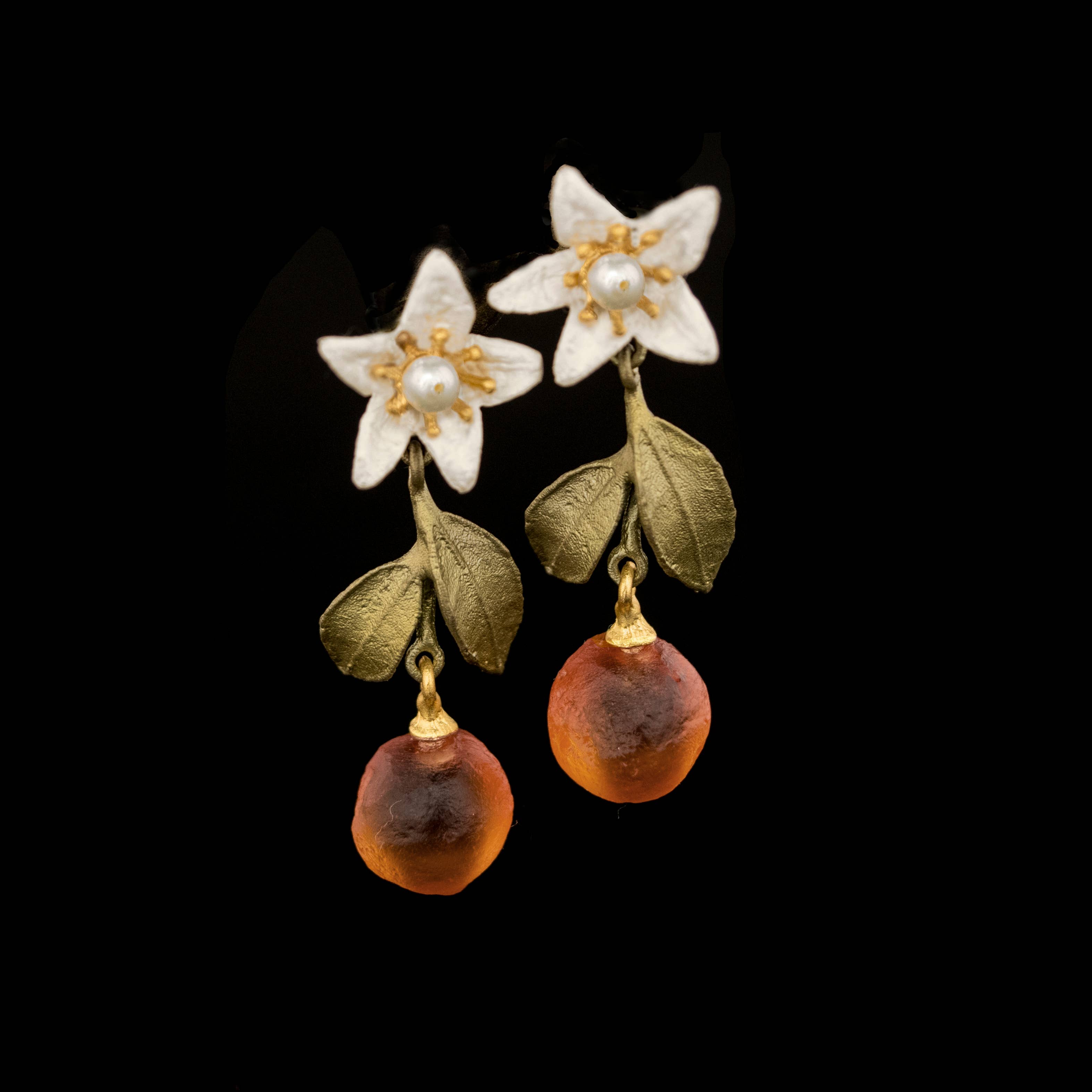 Pair of earrings with floral design and amber beads on a black background