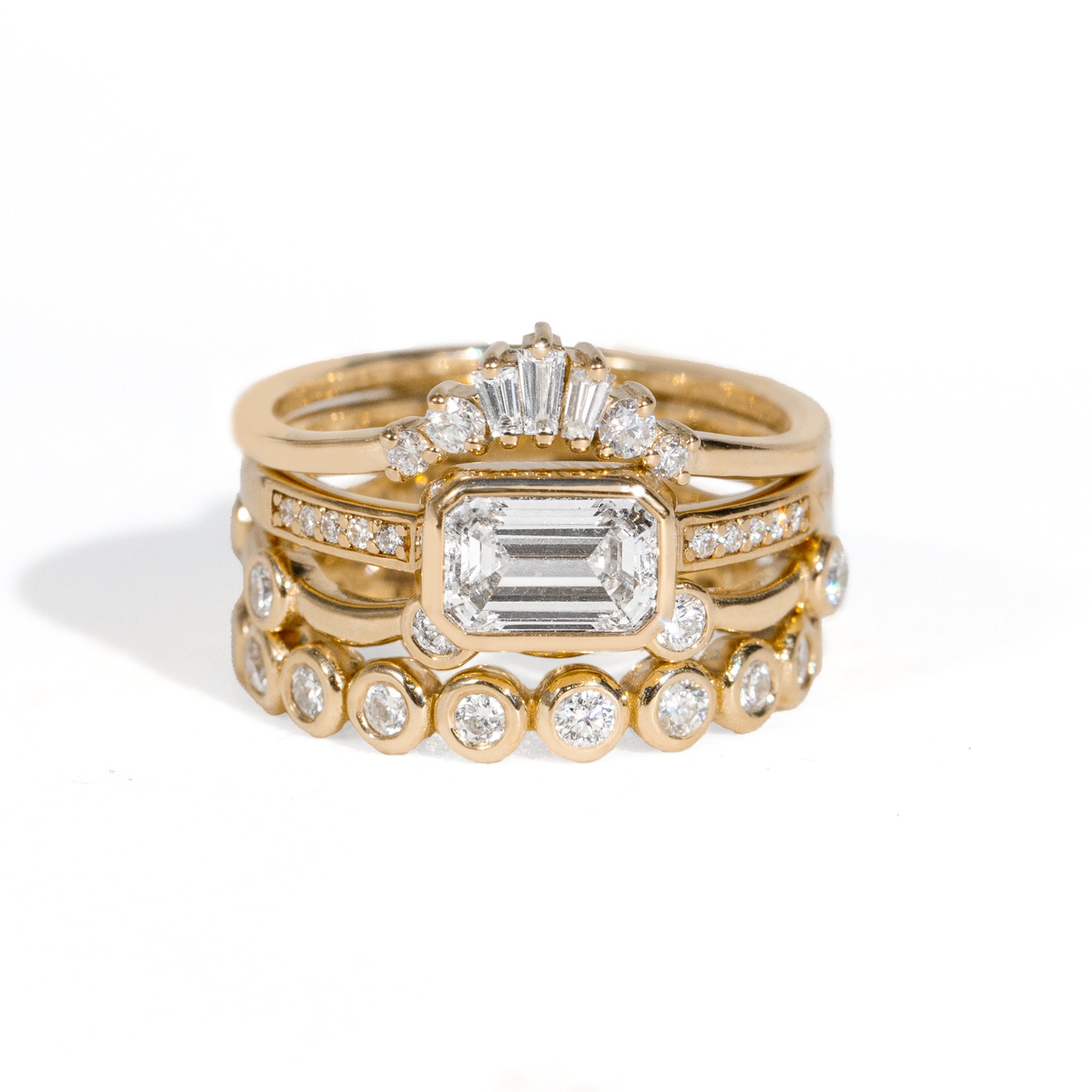 Stack of gold rings with diamond accents on a white background