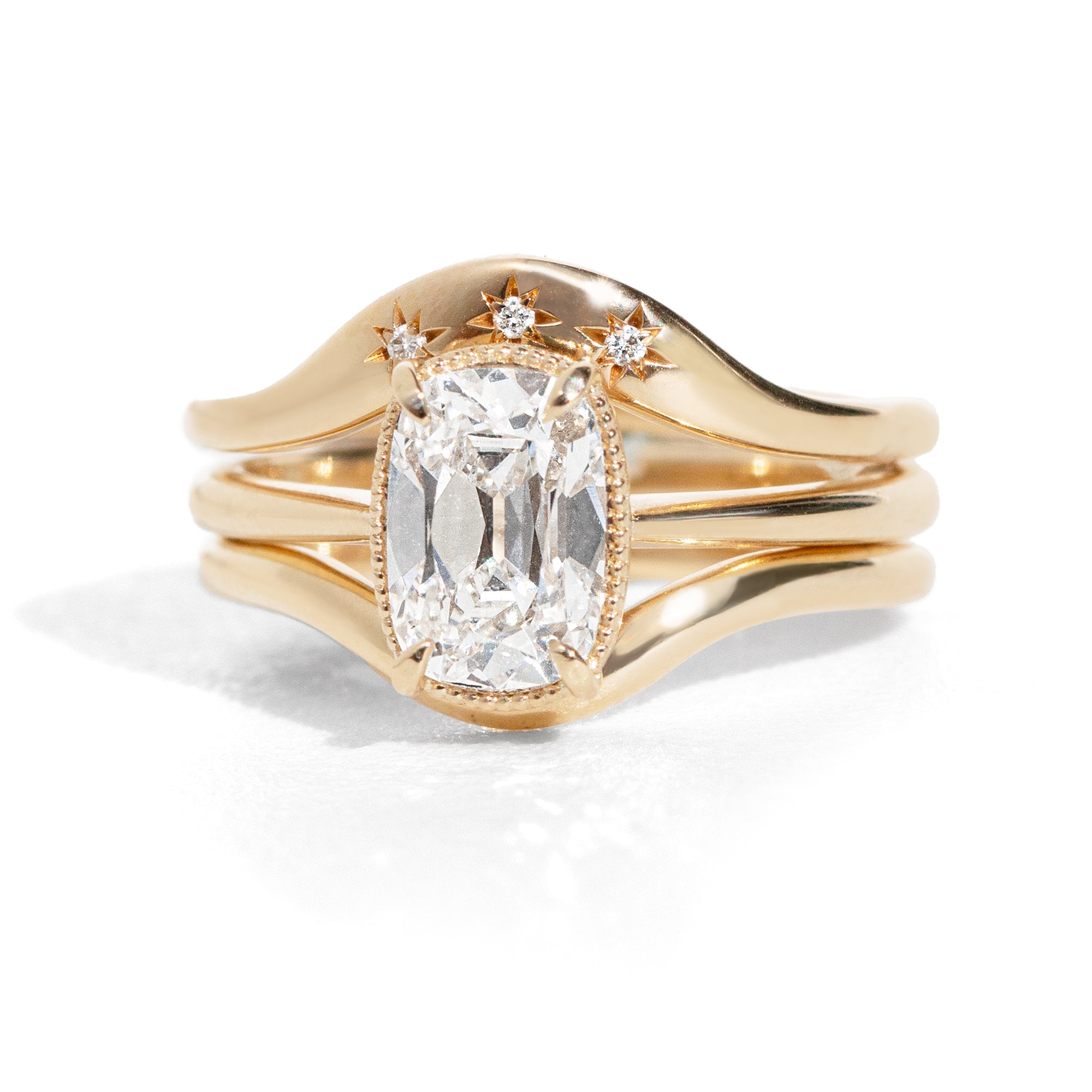 Old mine cut diamond ring stacked with contour wedding bands on a white background.