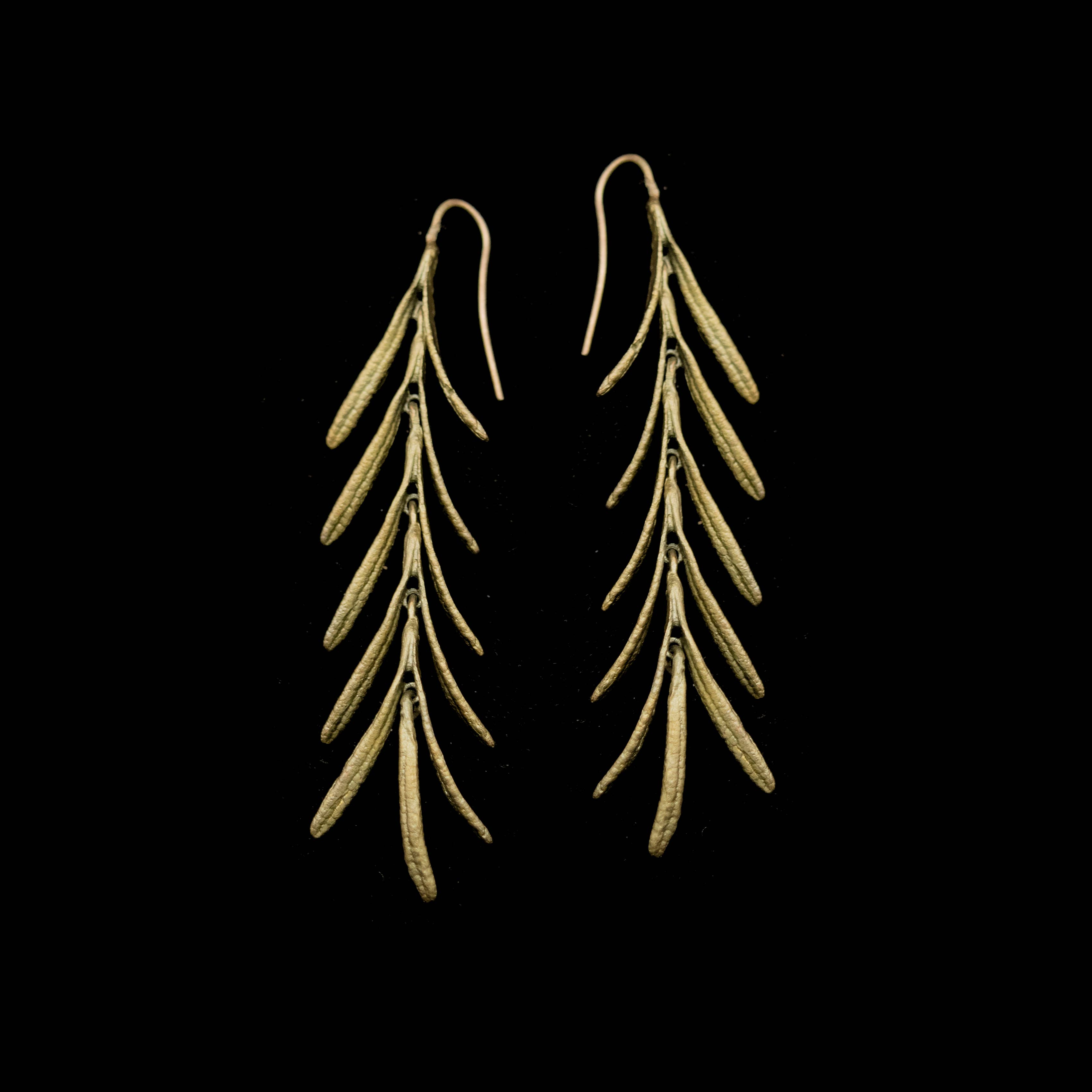Pair of gold leaf-shaped earrings on a black background