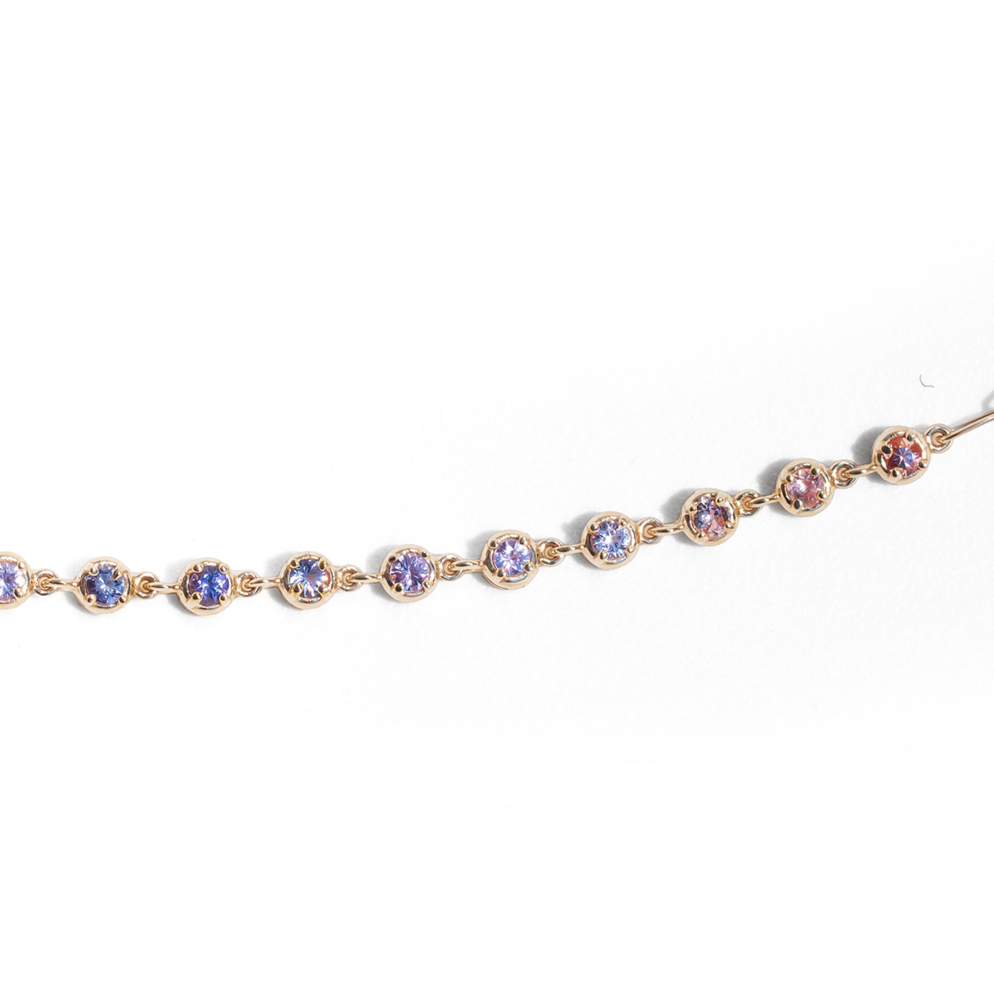 Gold bracelet with colorful gemstones on a white background