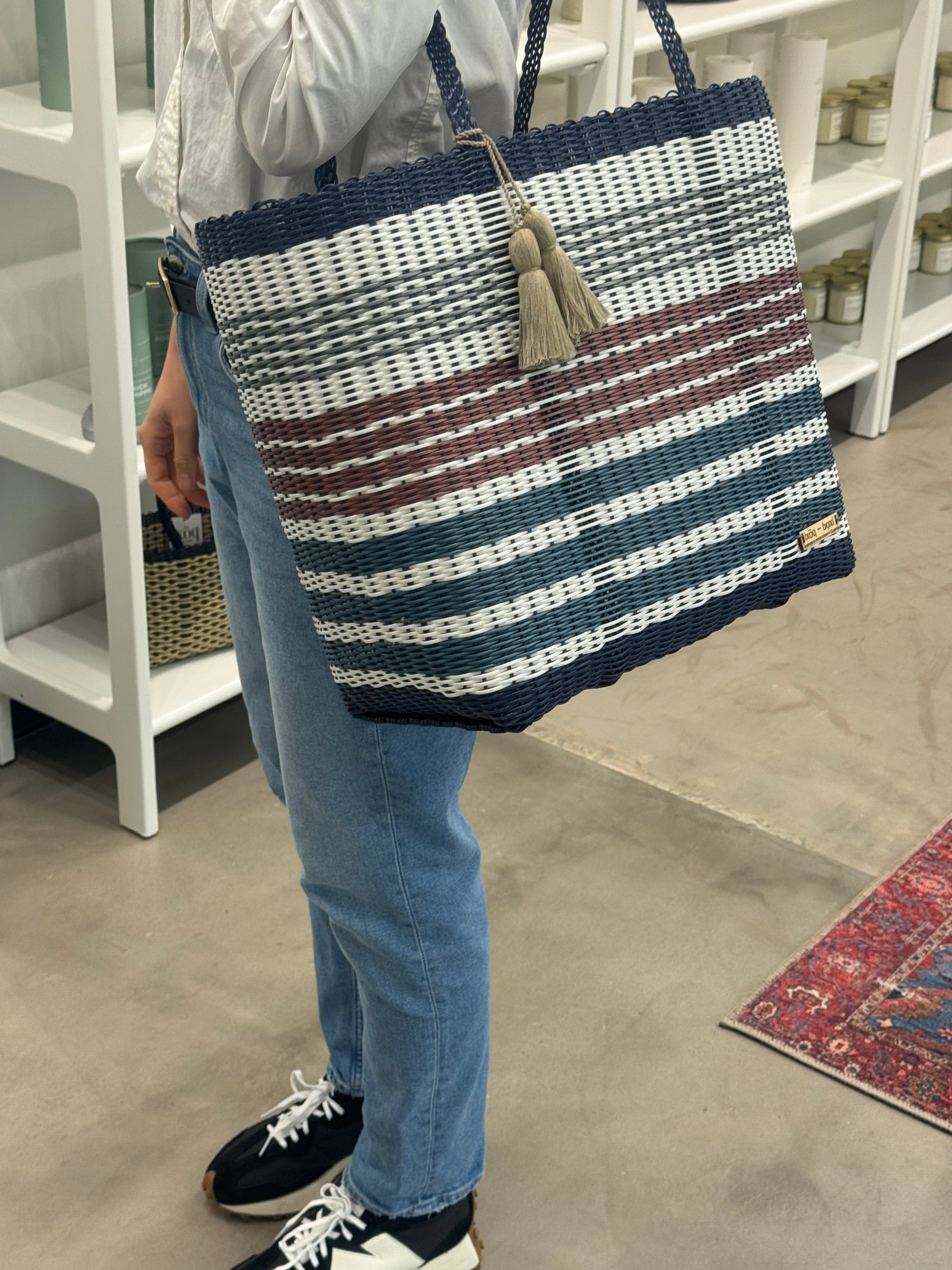 Person holding a striped tote bag in an indoor setting