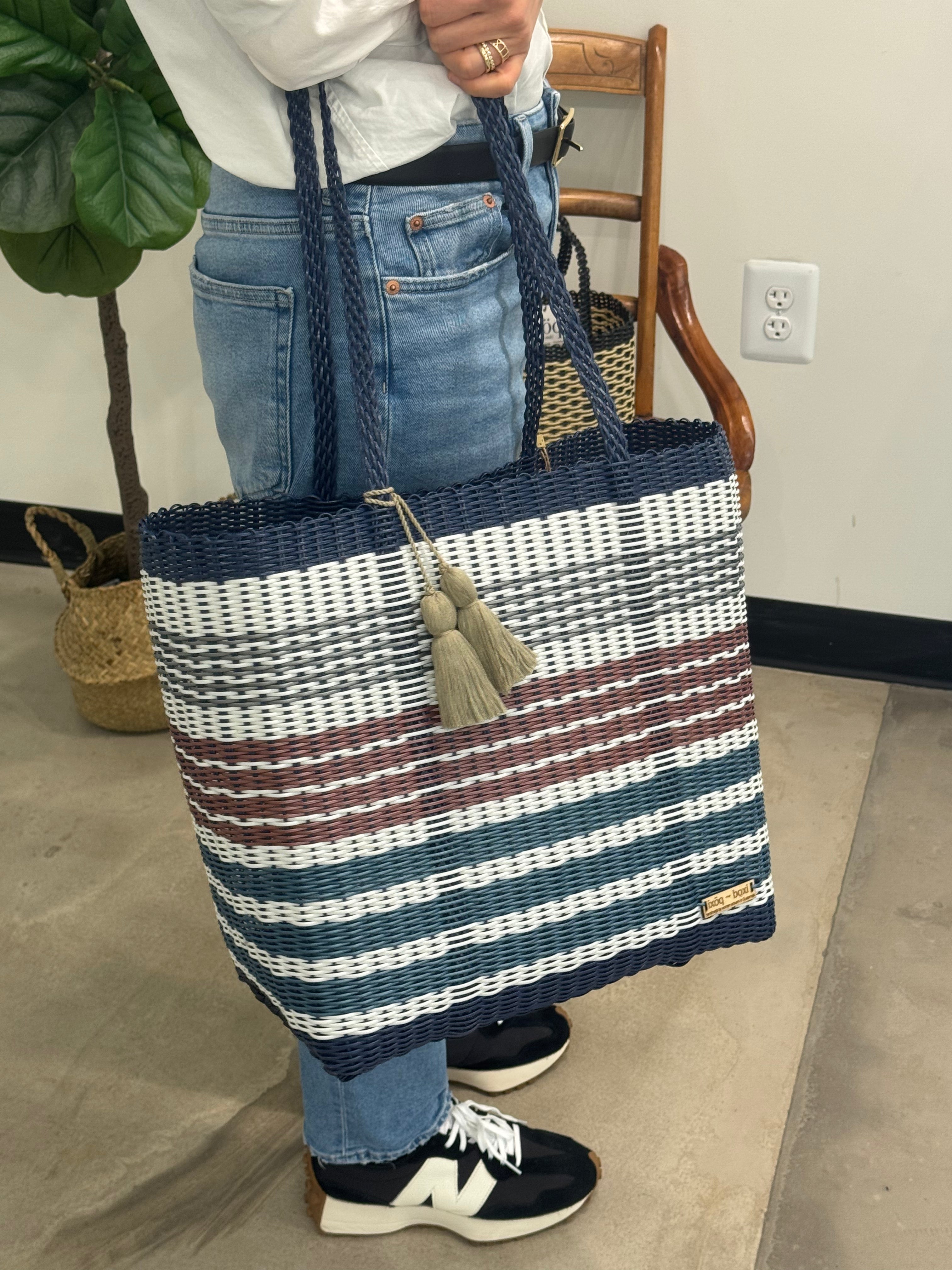 Person holding a striped tote bag in an indoor setting