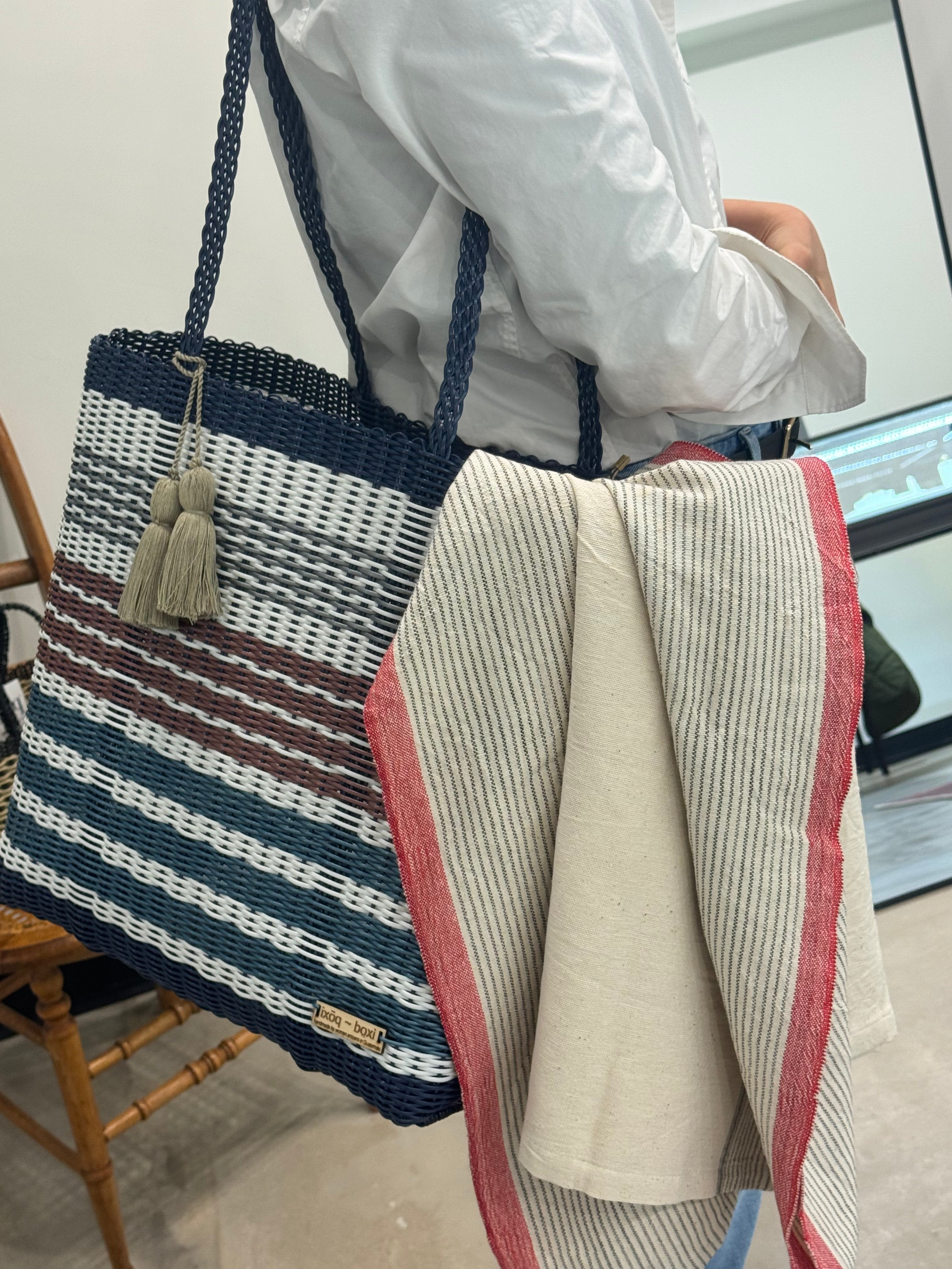 Person holding a striped bag with a chair and screen in the background