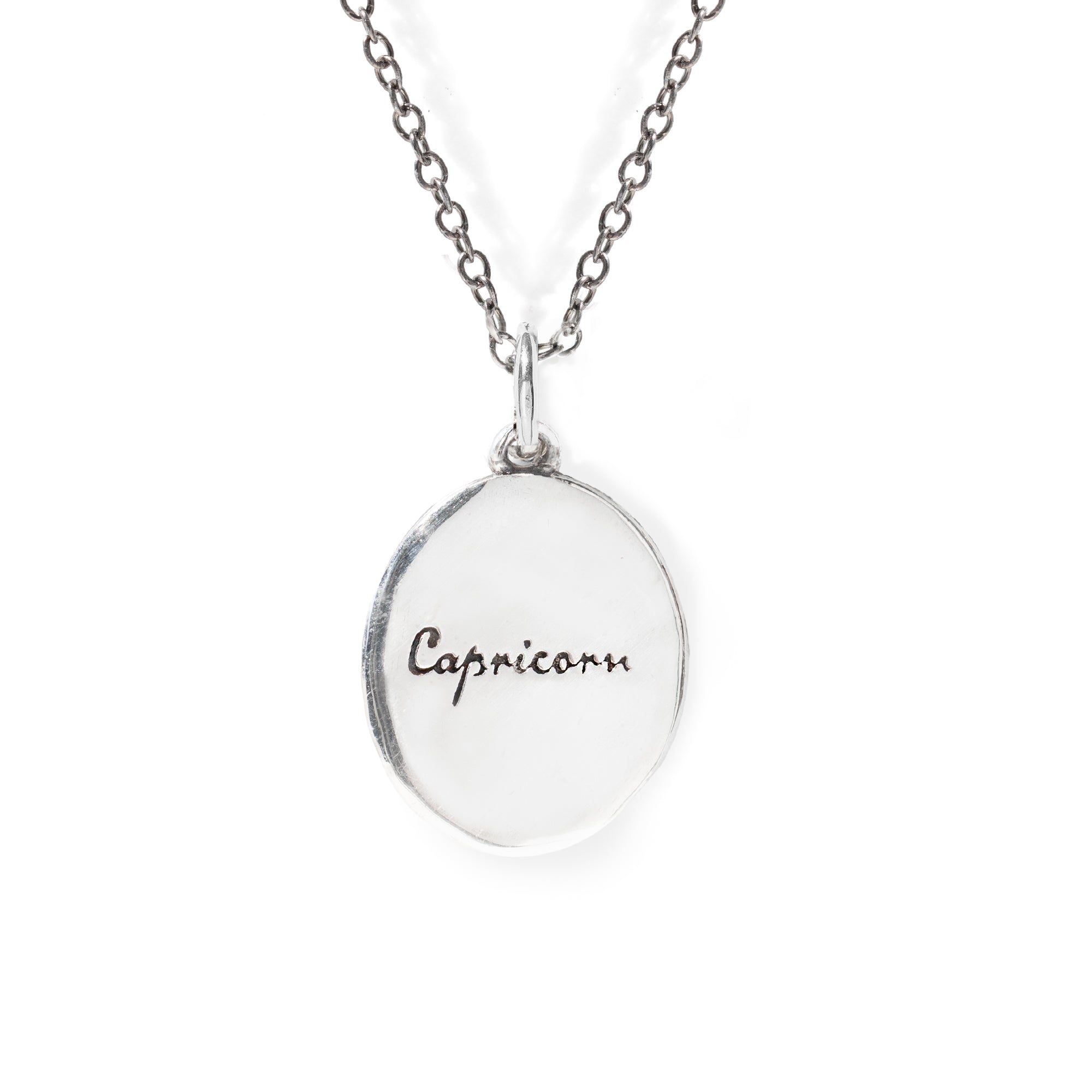 Silver necklace with a round pendant engraved with 'Capricorn' on a white background