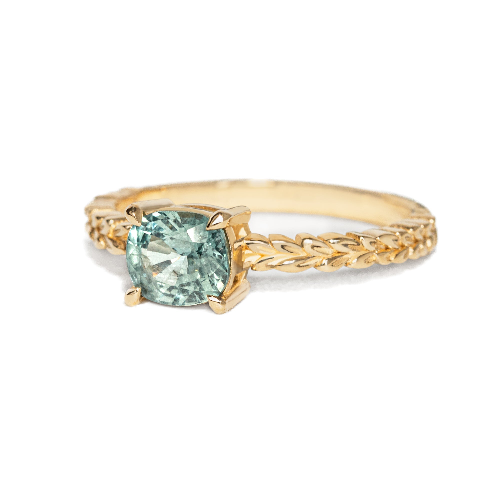 Jamie Park Jewelry -Meadow 1.16ct Cushion Montana Sapphire Ring Indulge in the beauty of nature with our Meadow Montana Sapphire Ring. Featuring a 1.16ct cushion cut sapphire, east-west set on an olive leaf band, this piece is perfect for an engagement ring or a special gift. The Montana sapphire's blue and green hues make it a truly one-of-a-kind piece to celebrate life's special moments.
