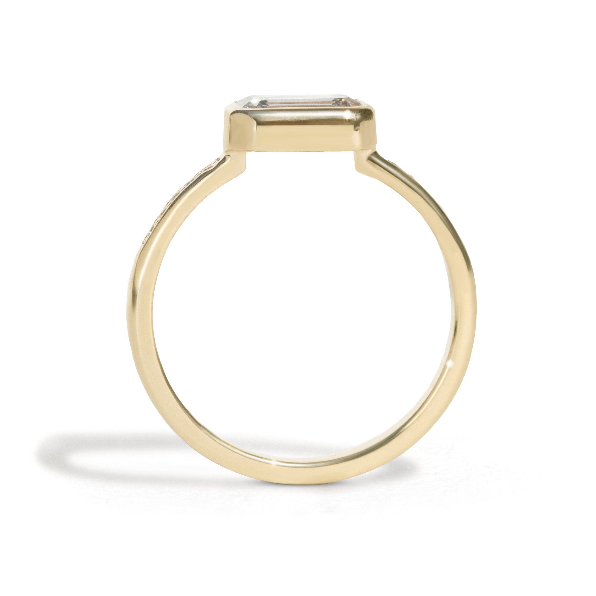 The Zoey Ring features a 1-carat emerald-cut diamond or moissanite in an east-west setting. The smooth bezel setting ensures everyday wear, while delicate accent diamonds add sparkle from every angle