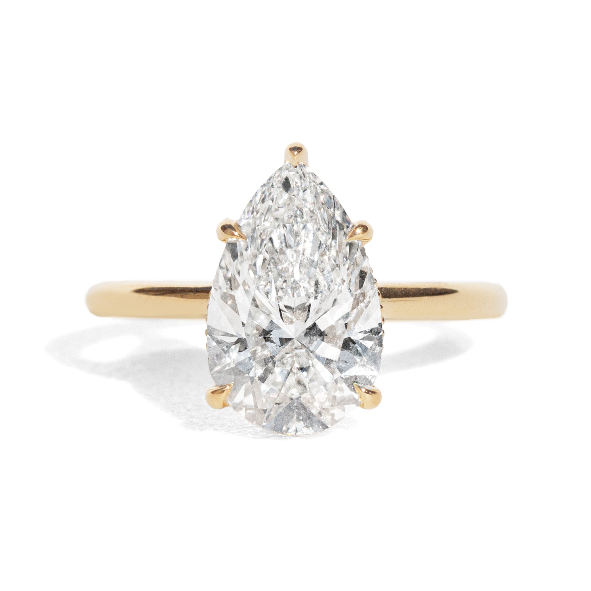 Gold ring with a pear-shaped diamond on a white background