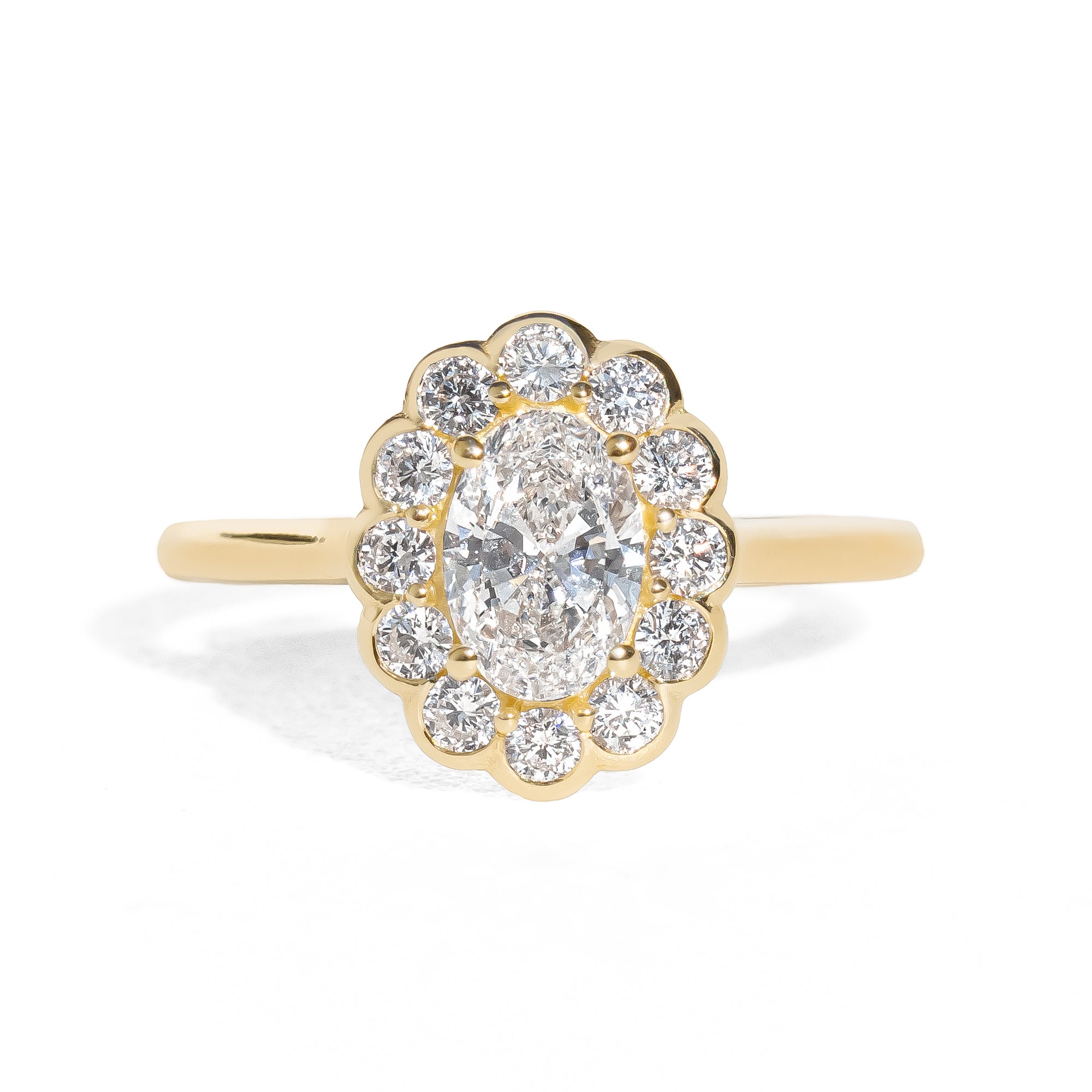 Gold ring with an oval diamond framed by small round halo diamonds on a white background