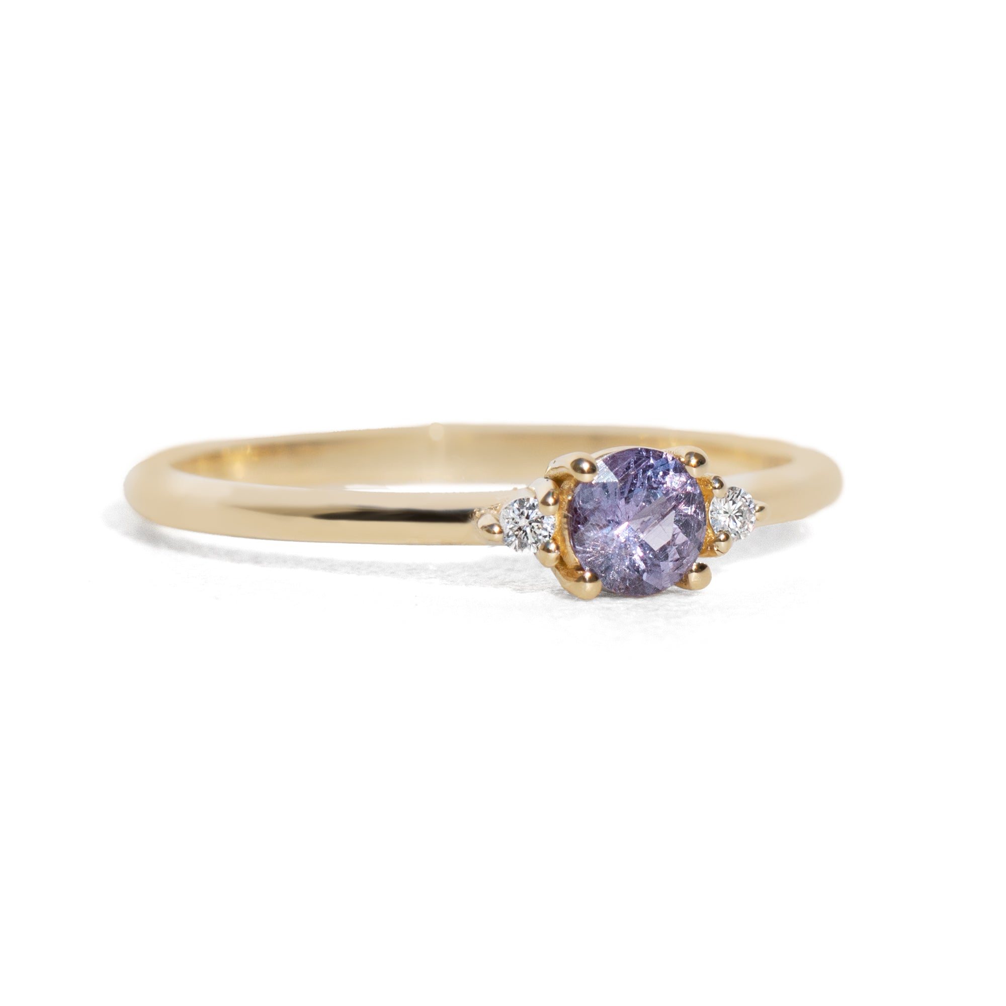 Gold ring with a purple gemstone on a white background