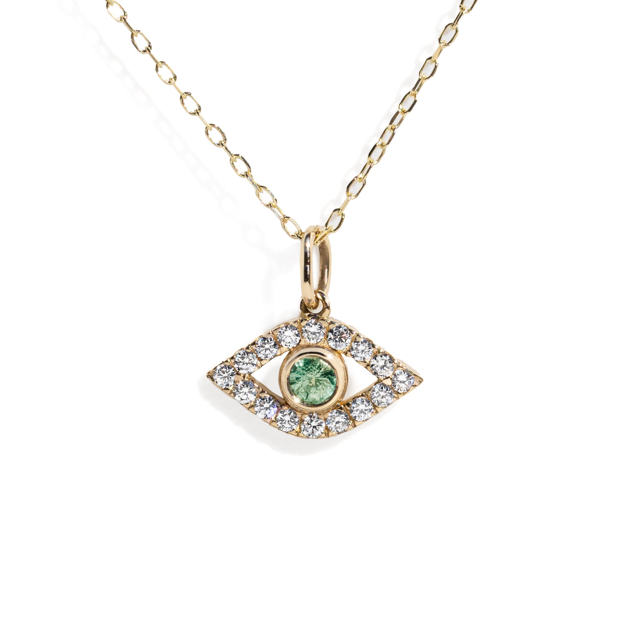 Gold eye charm with a green sapphire in the center surrounded by white diamond frame on a gold chain against white background.