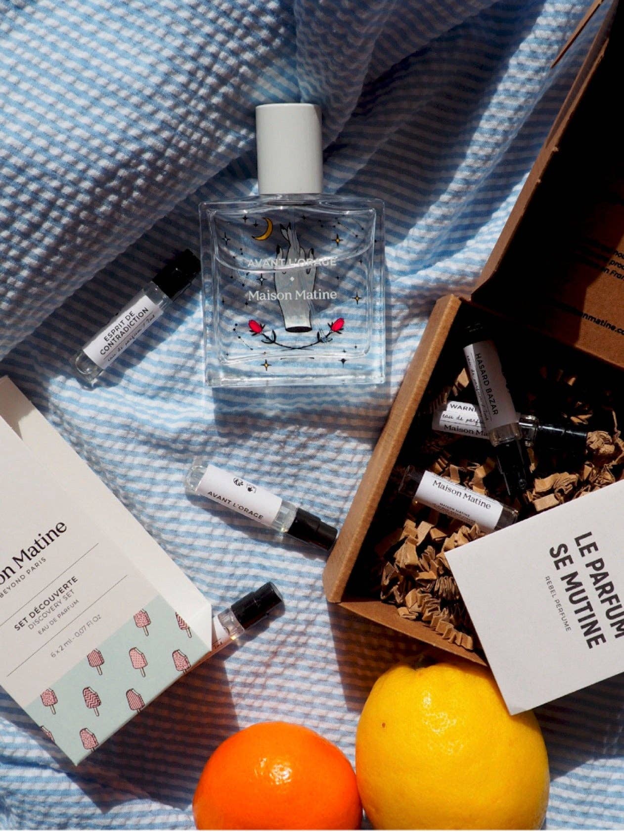 Perfume bottles and packaging on a textured surface with fruits