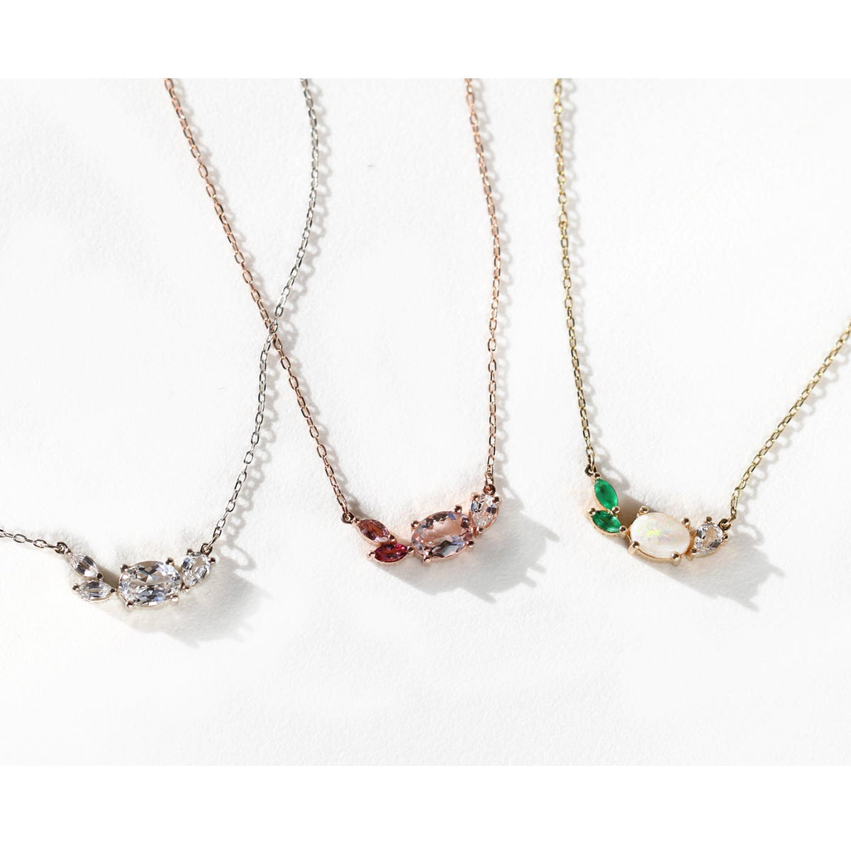 This beautiful, 14K gold-cast necklace is inspired by the tranquility of a lush evergreen. Adorned with a cluster of gorgeous gemstones, including an Australian opal and two emeralds, it's finished with a sparkly pear-cut lab diamond.