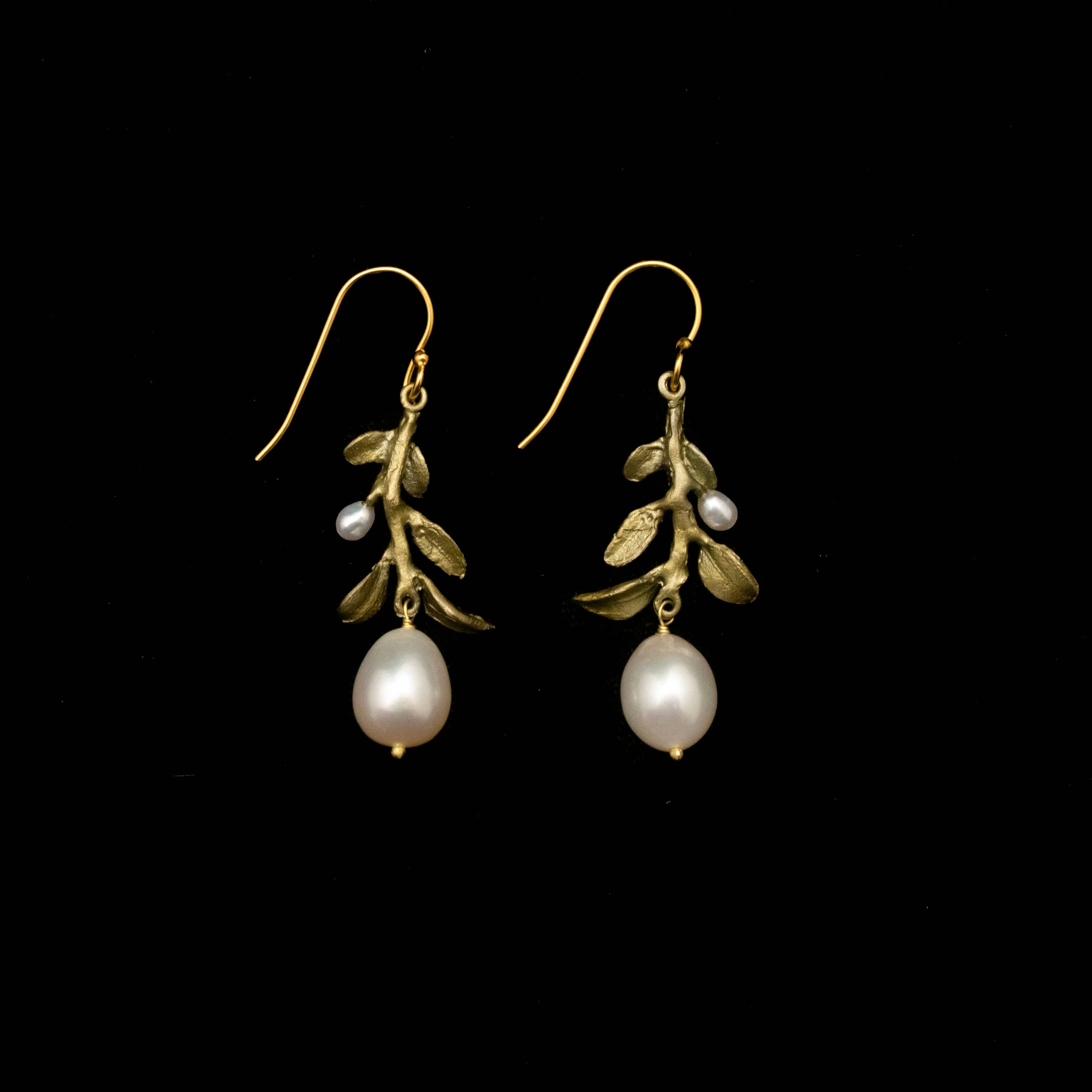 Pair of gold earrings with pearl drops on a black background