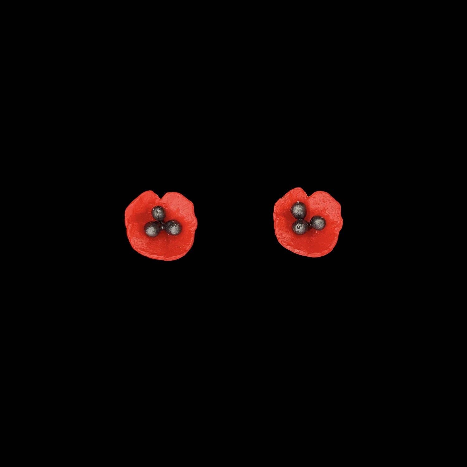 Red flower-shaped earrings on a black background