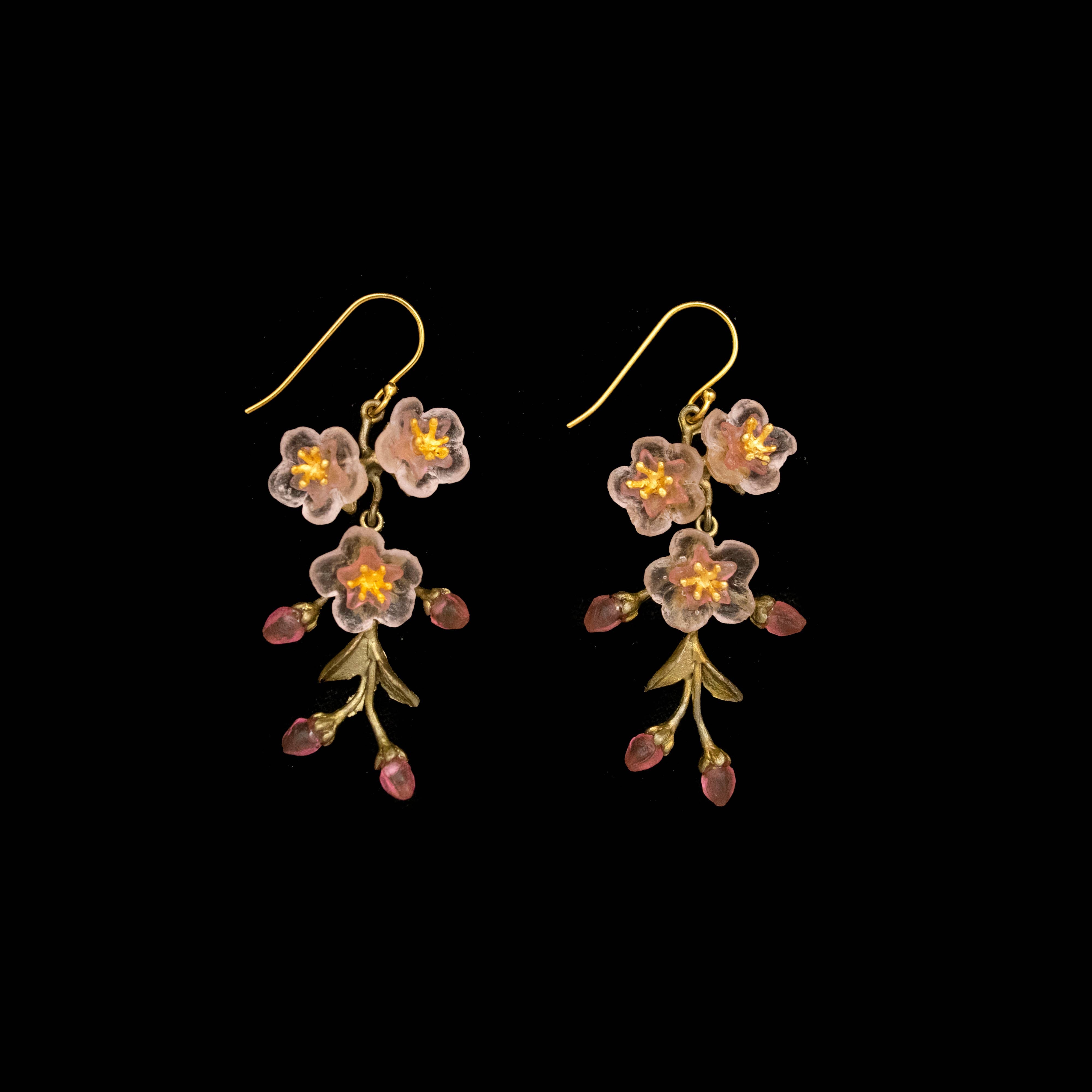 Floral earrings with pink flowers and green leaves on a black background
