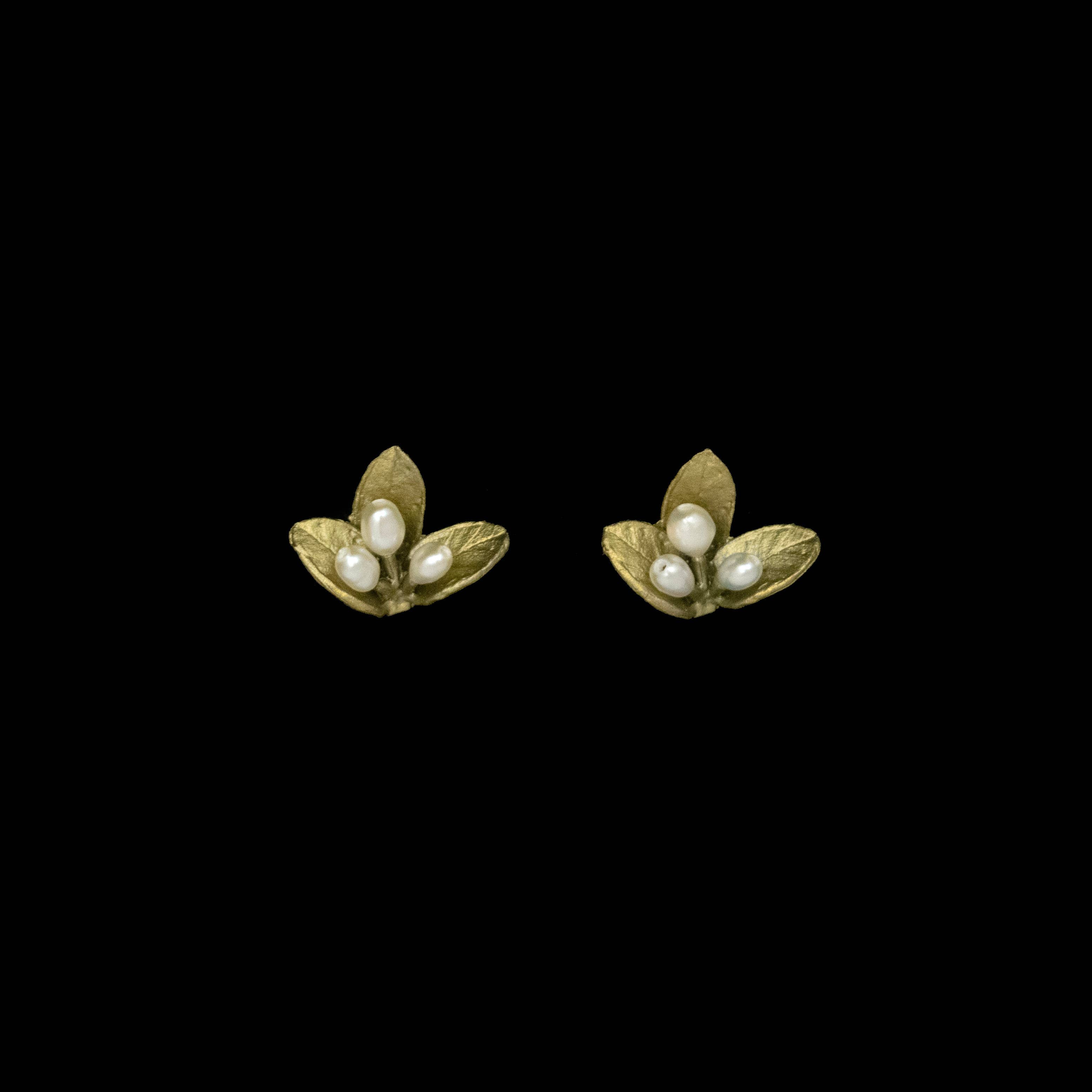 Pair of gold leaf-shaped earrings with pearl centers on a black background