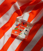 Perfume bottle with colorful design on a red and white striped fabric background