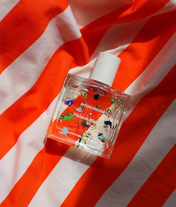 Perfume bottle with colorful design on a red and white striped fabric background