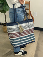 Person holding a striped tote bag in an indoor setting