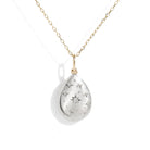 A teardrop-shaped silver pendant necklace with a gold chain, featuring a central diamond and star engravings, set against a plain white background.