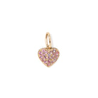 Heart-shaped gold charm with pink stones on a white background