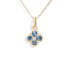Gold necklace with a flower-shaped pendant featuring blue gemstones on a white background