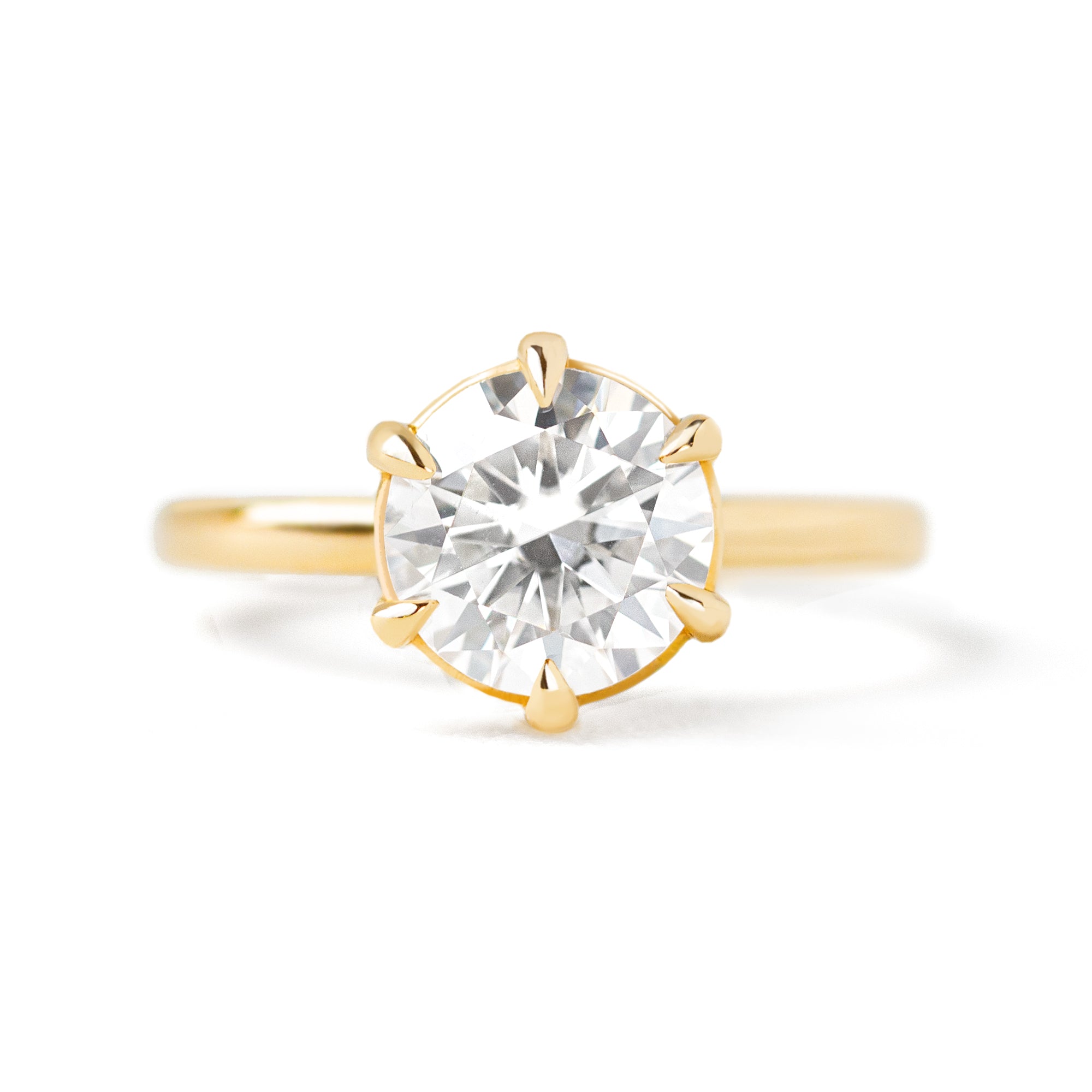 A gold solitaire ring with a round center diamond held by six prongs.