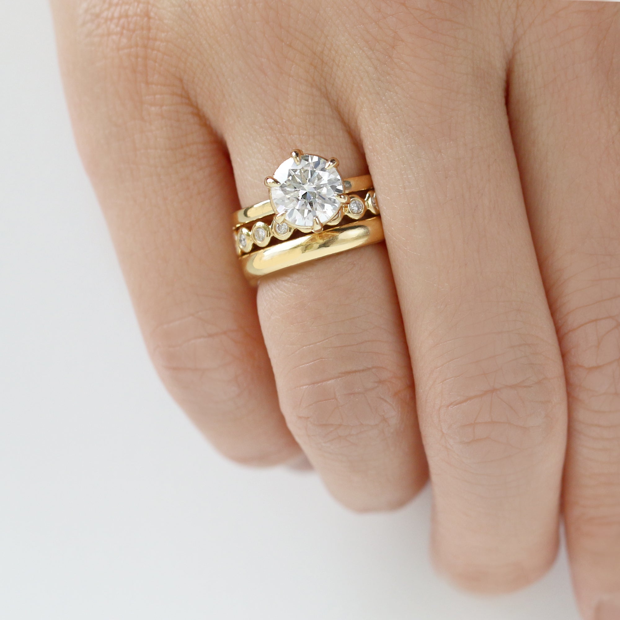 A gold solitaire ring with a round center diamond held by six prongs.