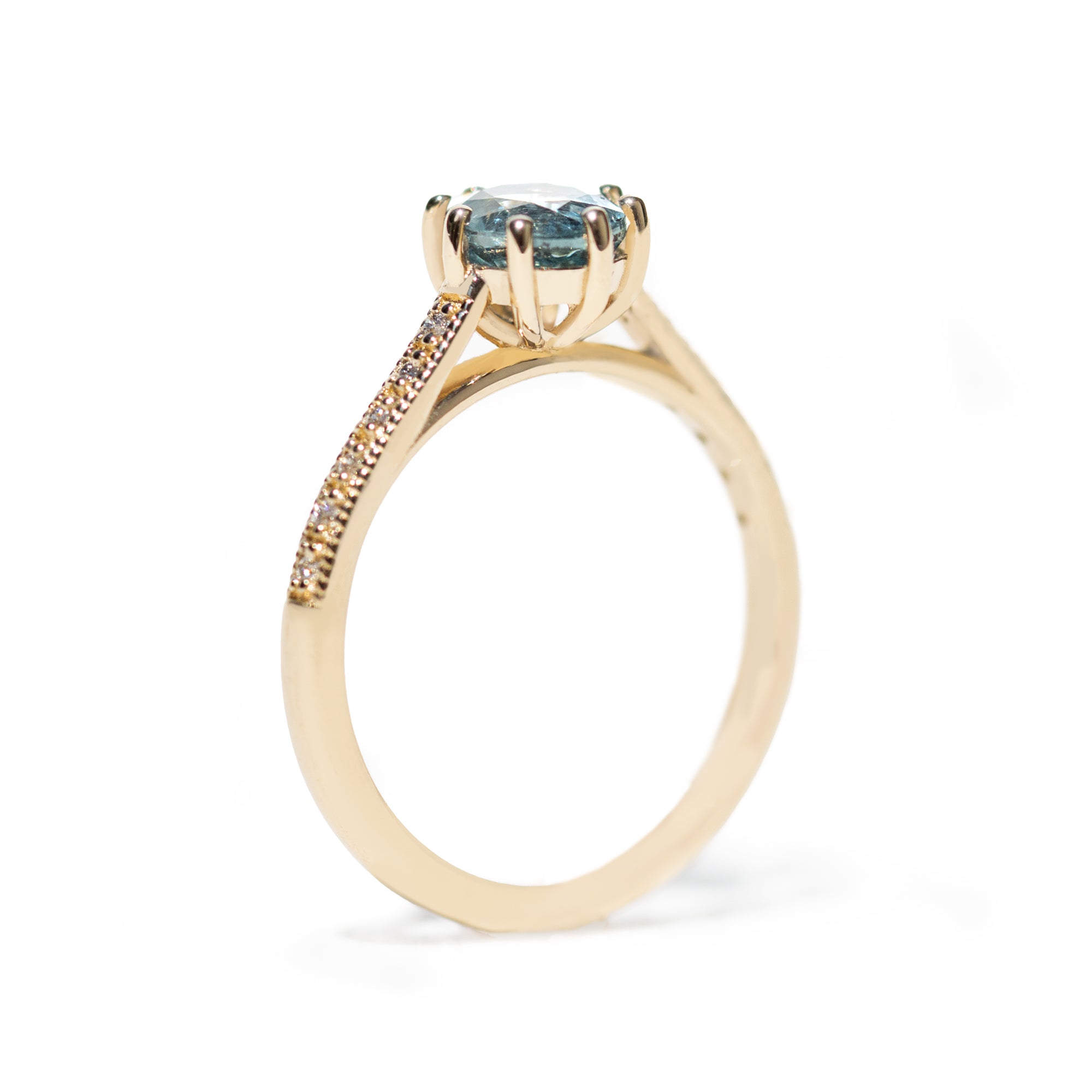 Gold ring with a blue gemstone and smaller diamonds on a white background