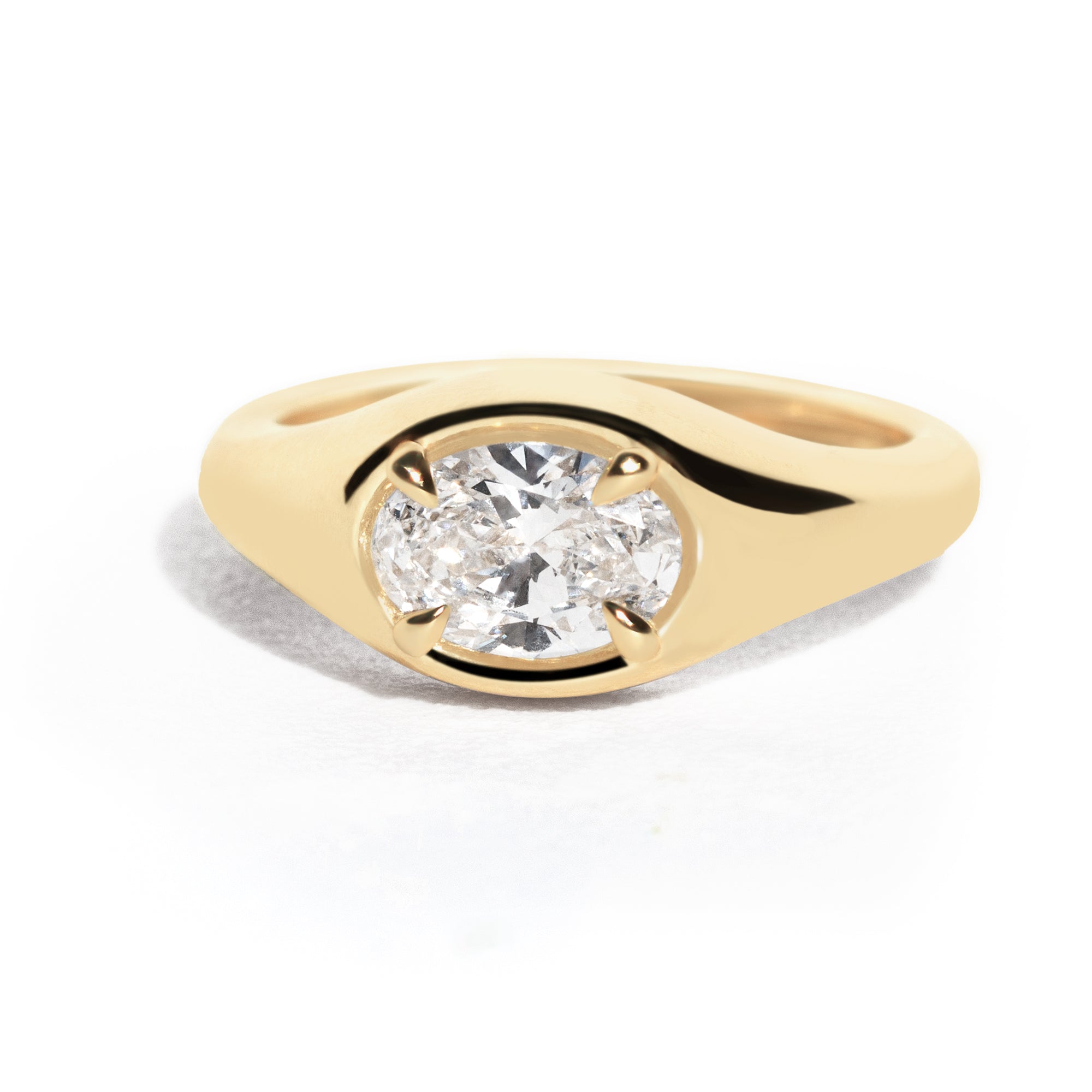 A gold band ring with an oval-shaped diamond set in an east-west orientation.