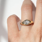 A gold band ring with an oval-shaped diamond set in an east-west orientation.