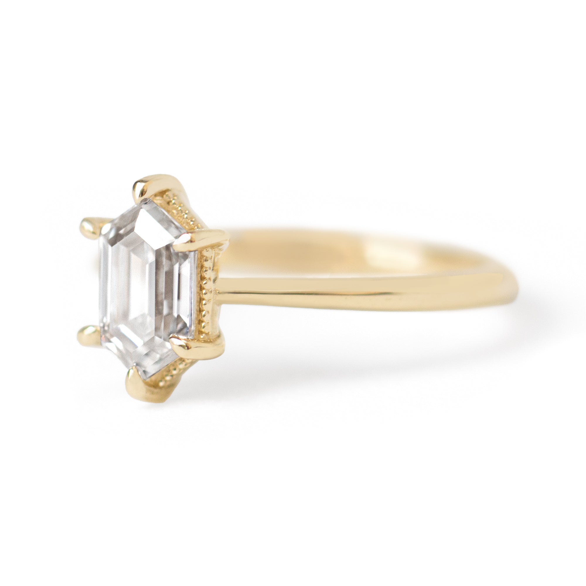 The Hera Ring showcases a 1.5ct hexagon lab diamond or moissanite, with a delicately highlighted hexagon step cut and milgrain accents on the setting. This elegant and romantic ring effortlessly combines antique charm with a modern aesthetic. It serves as the perfect choice for engagements, milestone celebrations, birthdays, and anniversaries, making it a versatile and timeless piece.