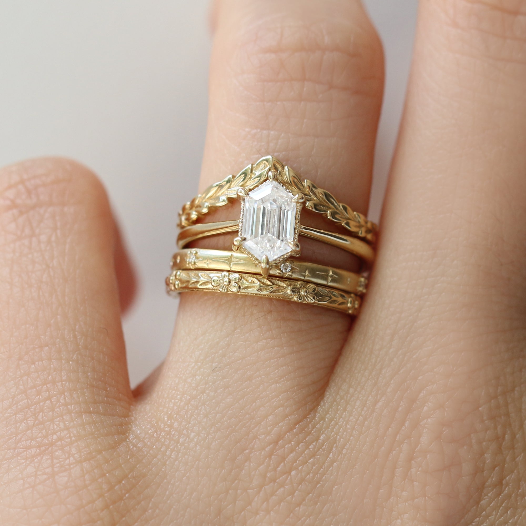 Gold ring with a diamond on a finger against a neutral background