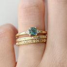 Gold ring with a blue gemstone on a finger against a neutral background