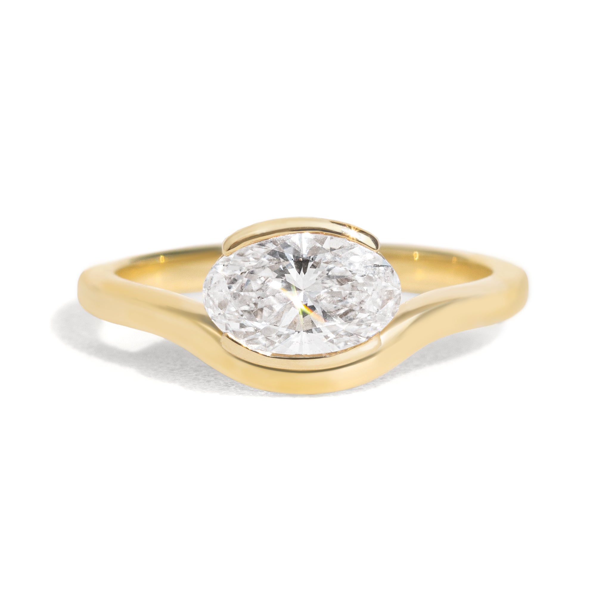 The Flow Ring features a 1 carat oval diamond or moissanite in a half bezel setting. The east west design adds a unique touch to this minimalistic design, making it the perfect subtle statement ring.