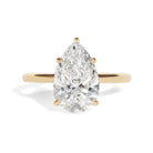 Gold ring with a pear-shaped diamond on a white background