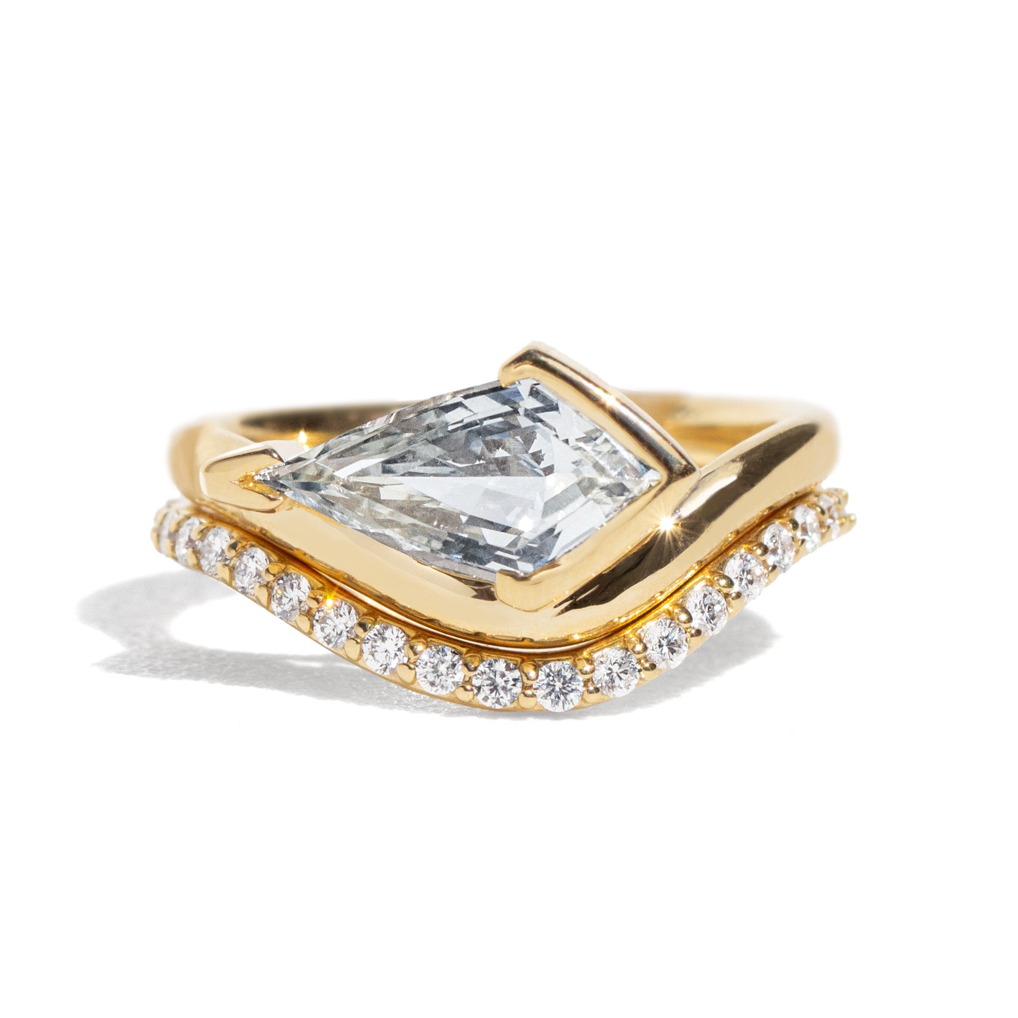 Gold ring with a large light blue sapphire and smaller diamonds on the band against a white background