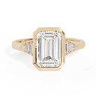 Gold ring with emerald-cut diamond and baguette diamonds on a white background