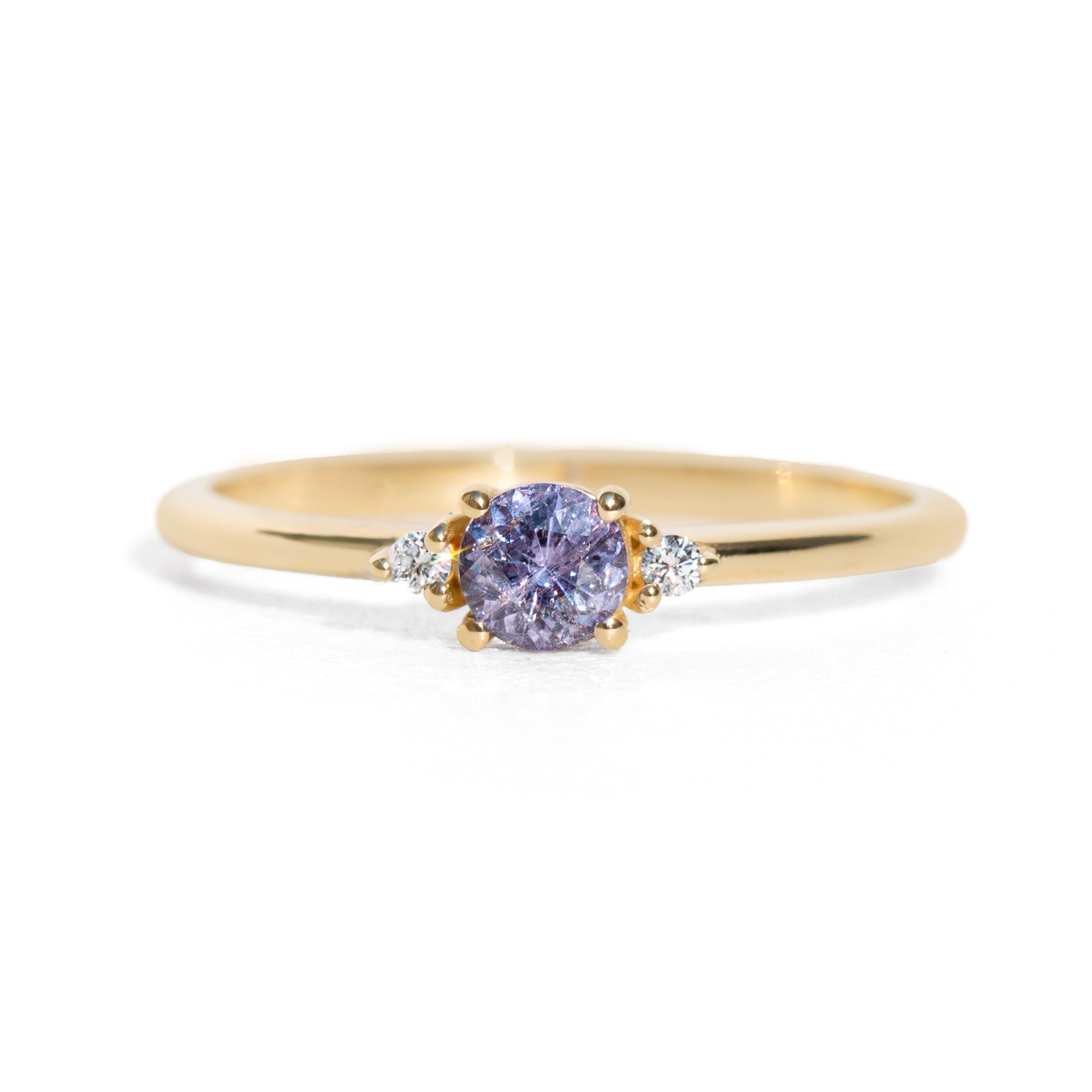 Gold ring with a purple sapphire on a white background