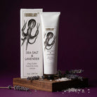 Shea butter hand and body crème with packaging on a wooden stand against a purple background