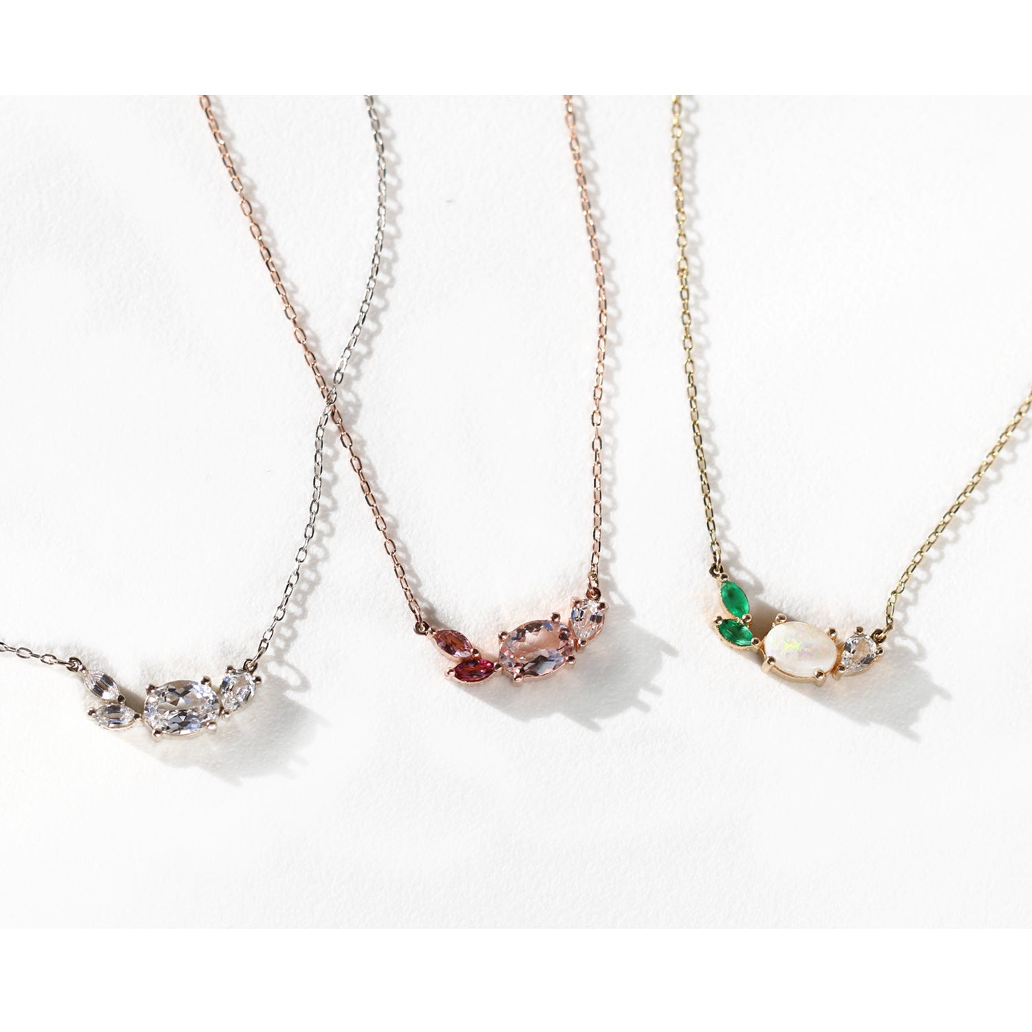 This beautiful, 14K gold-cast necklace is inspired by the tranquility of a lush evergreen. Adorned with a cluster of gorgeous gemstones, including an Australian opal and two emeralds, it's finished with a sparkly pear-cut lab diamond.