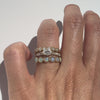 Hand wearing diamond band, diamond engagemeng ring and opal band