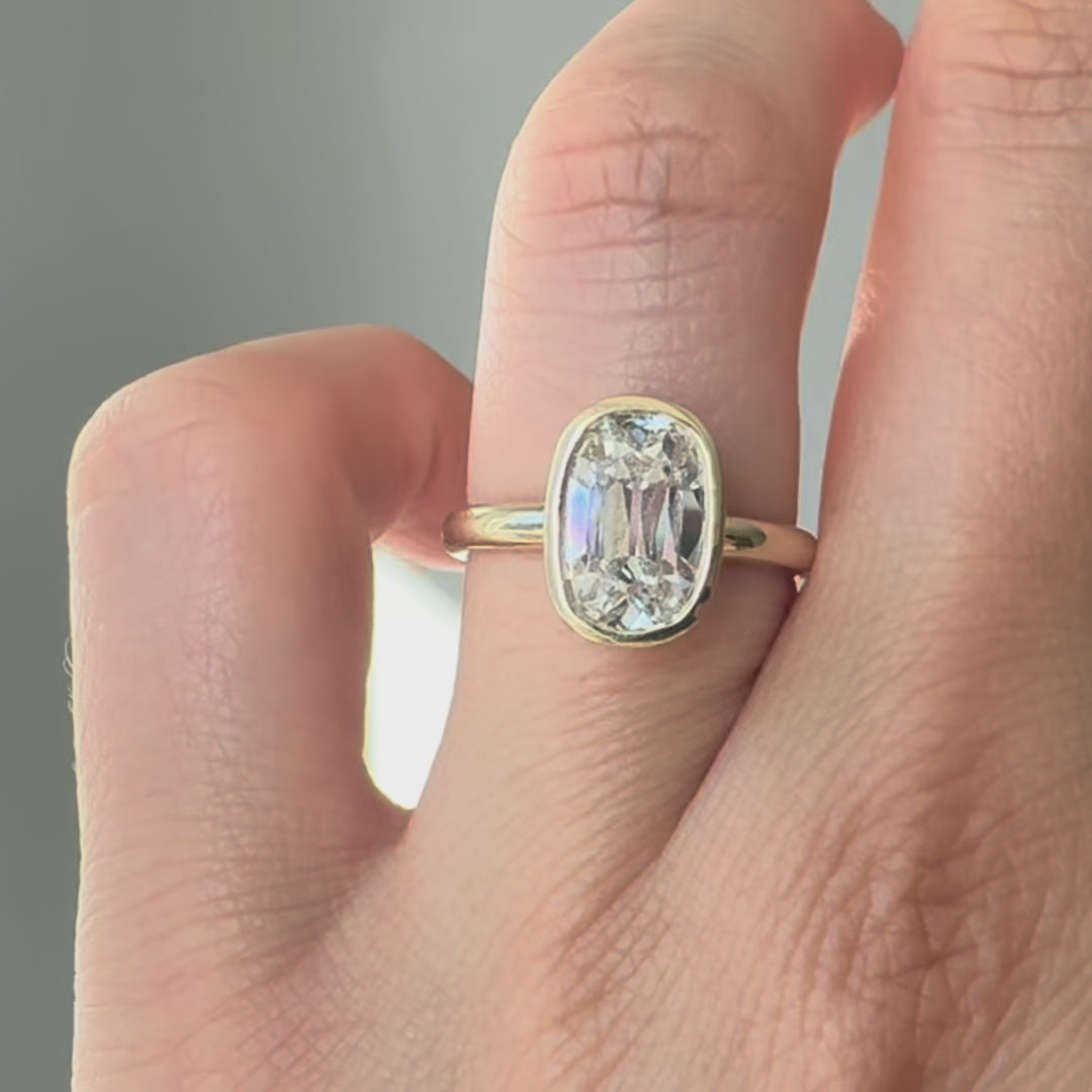 Gold ring with a large diamond on a finger against a neutral background