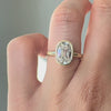 Gold ring with a large diamond on a finger against a neutral background