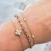 three gemstone bracelets worn on a wrist against a gray background