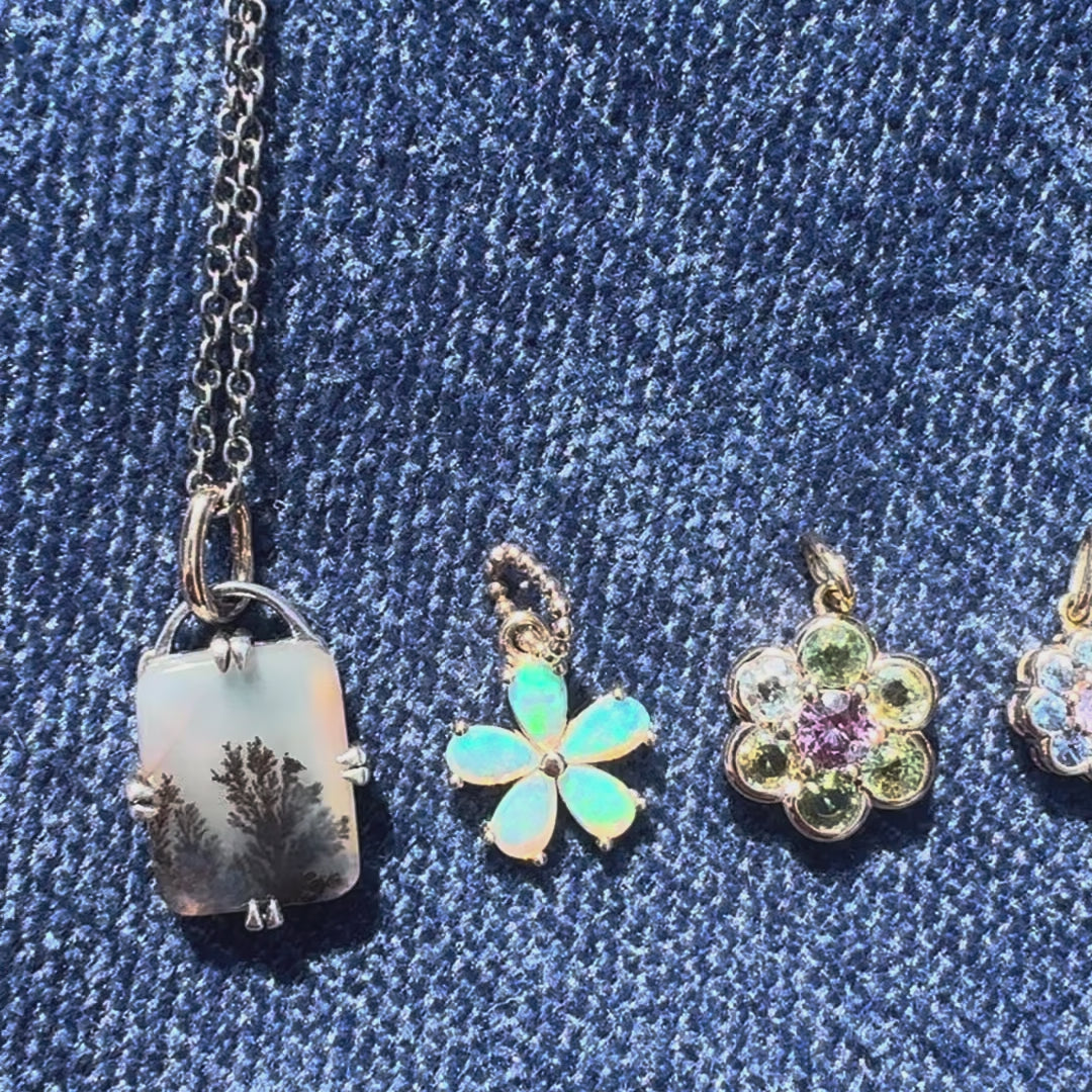 Five gemstone gold pendant against a blue background