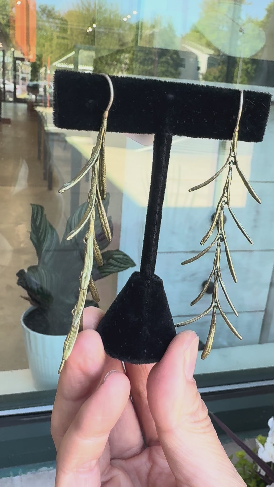 Leaf earrings against a storewindow
