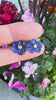 Blue flower earrings with gold accents against a floral background.