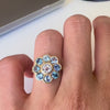 Gold ring with blue sapphires on a hand against white background
